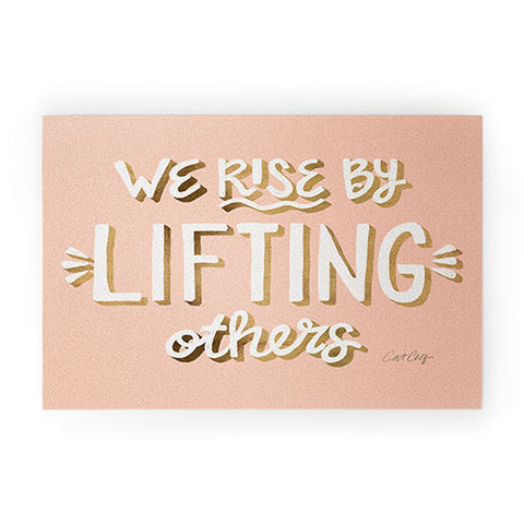 Cat Coquillette We Rise By Lifting Others Blush and Gold Welcome Mat